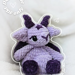 Peut inclure: Une peluche crochetée à la main dans des tons de violet et de violet foncé, en forme de créature à cornes. La peluche a une étoile sur la tête et de grands yeux noirs. L'image comprend le texte "Digital file PDF only."