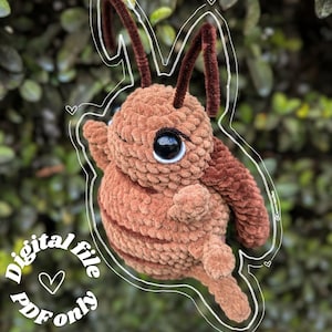 Peut inclure: Une peluche de fourmi marron crochetée avec de grands yeux noirs et des antennes marron foncé. La peluche est soulignée d'une bordure blanche et le texte "Digital file PDF only" est visible.