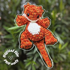 Peut inclure: Une peluche de dragon au crochet orange et blanc. Le dragon a un ventre blanc, des yeux noirs et une longue queue. L'image comprend le texte "Digital file PDF only".