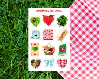 May include: A sheet of stickers with a picnic theme, including a ladybug on a leaf, a strawberry, a camera, a sandwich, a playing card, a picnic basket, a book, a heart-shaped bowl, a bow, and a heart. The text "My Cutie Journal" is at the top.