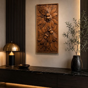 May include: A rectangular wooden wall art piece with a detailed relief carving of bees and flowers. The artwork is in shades of brown and is mounted on a neutral-coloured wall. The piece adds a natural element to the room's decor.