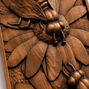 May include: A detailed wooden carving of a bee on a flower. The bee is intricately carved, showing wings, legs, and body segments. The flower petals are also precisely carved, displaying the natural wood grain. The artwork is framed.