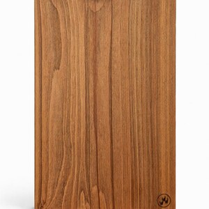 May include: A rectangular wooden board with a warm brown finish and vertical wood grain. A brass sawtooth hanger is attached to the top. A small circular logo is in the bottom right corner.