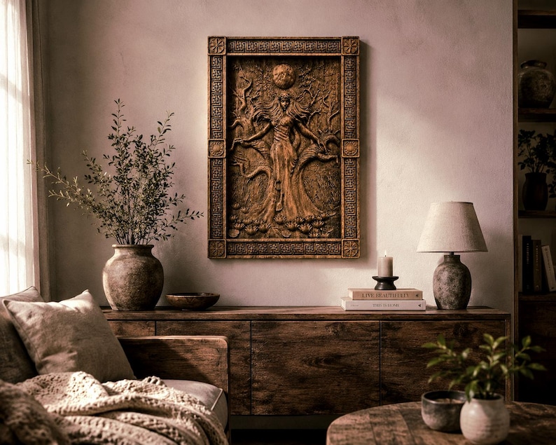 May include: A detailed, brown wooden wall art piece depicting a figure with outstretched arms, surrounded by trees and a sun. The art is framed and mounted on a neutral-toned wall, above a wooden cabinet. A lamp, books, and a candle are also visible.