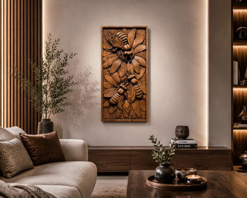 May include: A rectangular wooden wall relief depicting three bees and a flower, carved in detail. The artwork has a warm brown hue, with textured surfaces and shadows. The piece is mounted on a neutral wall, offering a nature-inspired decorative element. The dimensions are in centimeters.