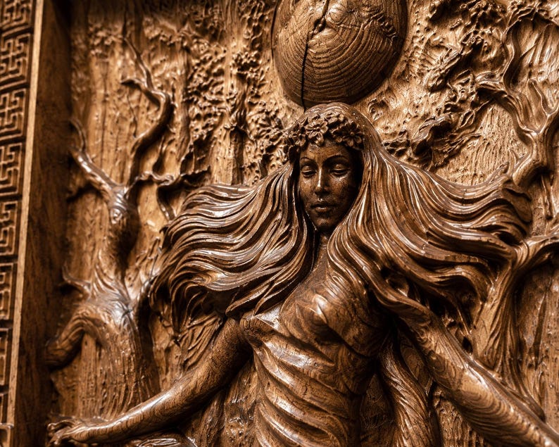 May include: A detailed wood carving depicts a woman with flowing hair, a floral crown, and outstretched arms. The artwork features a celestial body and a forest backdrop, all rendered in shades of brown.