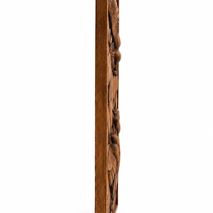 May include: A rectangular wooden wall panel with a carved relief design. The relief features a detailed botanical pattern of leaves, flowers, and fruit. The wood has a warm, medium brown tone, and the carving is visible from the side.