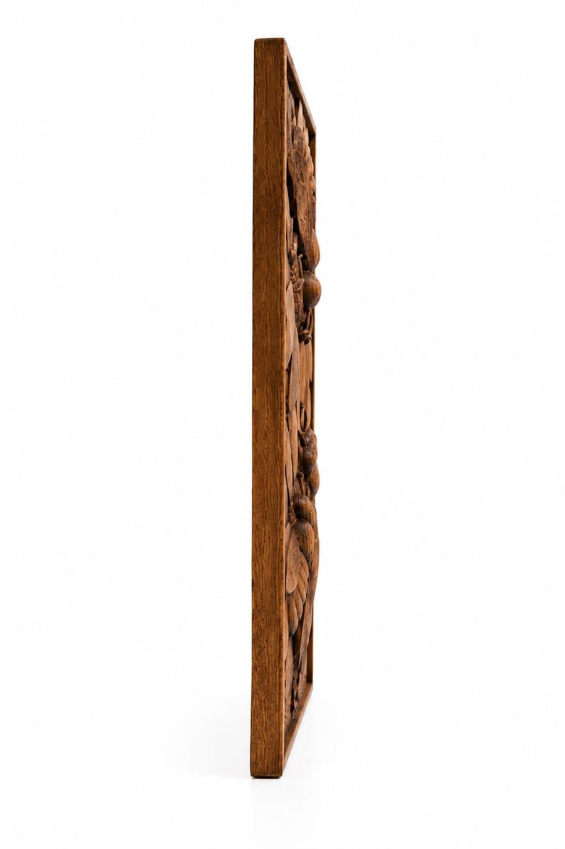 May include: A rectangular wooden wall panel with a carved relief design. The relief features a detailed botanical pattern of leaves, flowers, and fruit. The wood has a warm, medium brown tone, and the carving is visible from the side.
