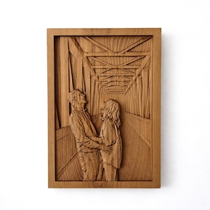 May include: A framed wooden relief carving of a couple embracing on a bridge. The artwork is carved from light-coloured wood, showing the bridge's architectural details and the figures' expressions. The figures are in the foreground, with the bridge receding into the background.