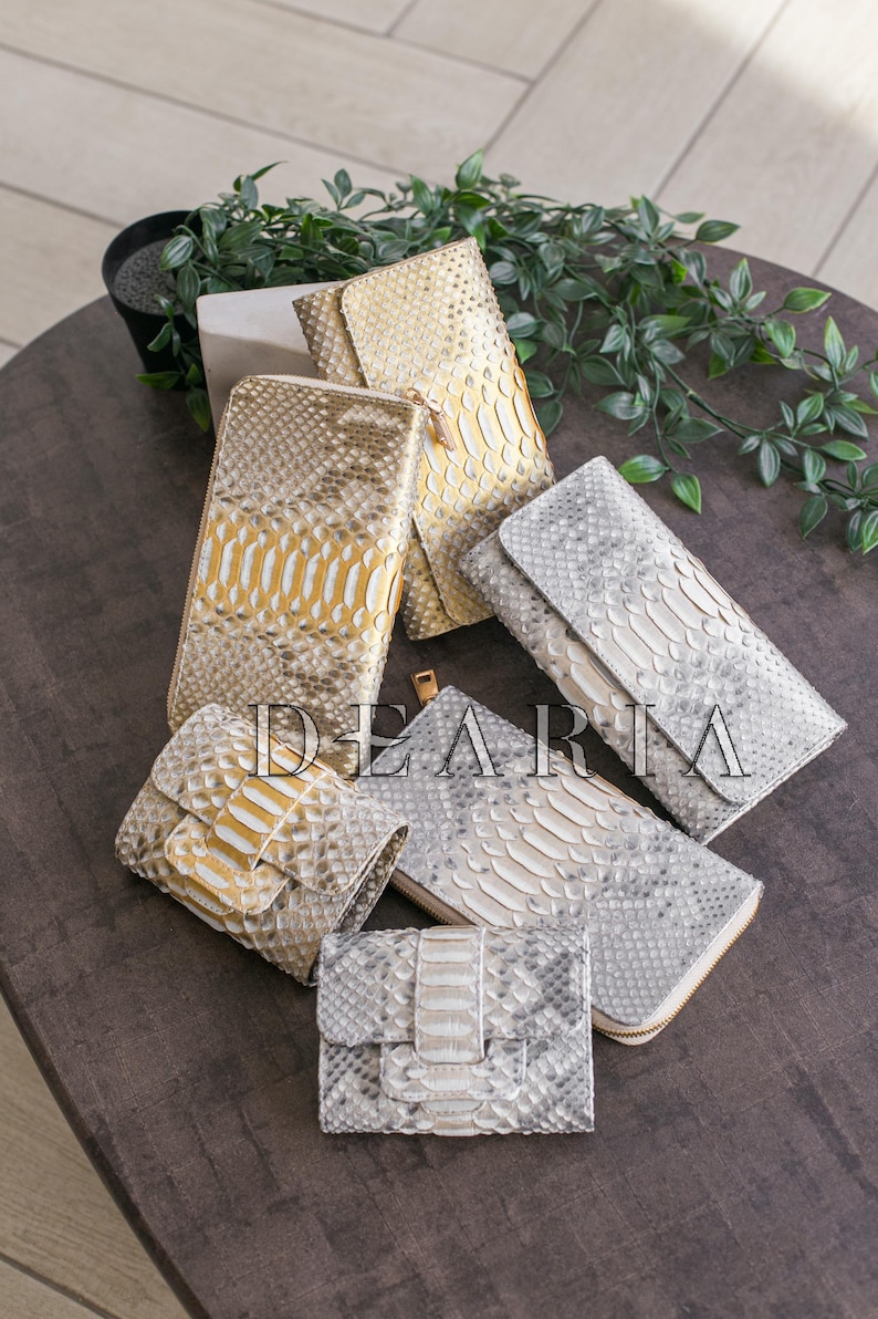 A collection of different snakeskin wallets in various shades of gold and silver.