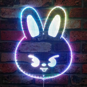May include: A neon light shaped like a cartoon bunny face, with a colorful outline and internal details. The light is mounted on a brick wall, with the neon colors including blue, purple, and yellow.