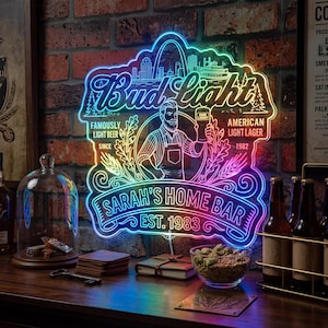 May include: A neon sign with the Bud Light logo, a cityscape, and the text "SARAH'S HOME BAR EST. 1983." The sign is illuminated with a gradient of colors and features an illustration of a man holding a beer.