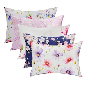 May include: Five decorative pillowcases with floral patterns. The pillowcases feature a variety of floral designs, including pink and white blossoms, blue and white flowers, and white flowers with pink and purple accents.