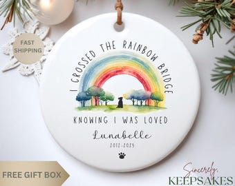 May include: White ceramic ornament with a rainbow, trees, and a black dog silhouette. Text reads "I Crossed the Rainbow Bridge, Knowing I Was Loved, Lunabelle 2012-2025." Includes a paw print.