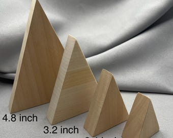 May include: Four wooden triangular prisms of varying sizes. The largest is 4.8 inches tall, the next is 3.2 inches, then 2.4 inches, and the smallest is 1.6 inches. The prisms are made of light-colored wood and are displayed against a gray background.
