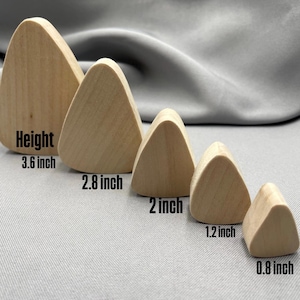Può includere: Cinque forme triangolari in legno di varie dimensioni, da 2 cm a 9,1 cm di altezza. Le forme sono marroni chiare e disposte in fila, con le misure dell'altezza in nero.