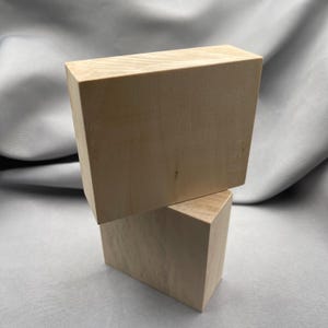 Może przedstawiać: Zestaw trzech ceramicznych kubków z nakrapianym, matowym wykończeniem. Kubki są w odcieniach kremu, jasnoszarym i ciemnoszarym. Każdy kubek ma prosty, nowoczesny design i zaokrąglony uchwyt.