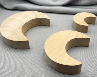 Könnte beinhalten: Drei halbmondförmige Holzobjekte in unbehandeltem Zustand. Das Holz ist hell, möglicherweise Buche oder ähnlich, mit einer glatten Oberfläche. Die Formen sind unterschiedlich groß, wobei sich das größte Objekt im Vordergrund befindet.