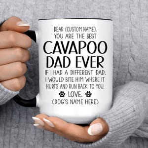 May include: A white ceramic mug with a black handle and rim, featuring black text that reads: DEAR (CUSTOM NAME), YOU ARE THE BEST CAVAPOO DAD EVER IF I HAD A DIFFERENT DAD, I WOULD BITE HIM WHERE IT HURTS AND RUN BACK TO YOU. LOVE, (DOG'S NAME HERE).