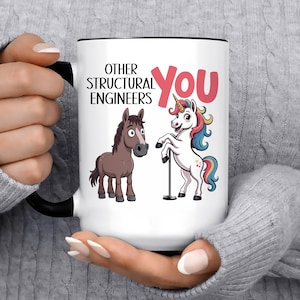 May include: A white ceramic mug with a black handle and rim featuring a cartoon brown horse and a colorful unicorn on a pole. The text reads OTHER STRUCTURAL ENGINEERS in black and YOU in large pink letters, creating a humorous comparison design.