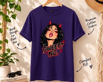 May include: A dark purple short-sleeved t-shirt featuring a graphic illustration of a person with black hair and red devil horns. The text "SWEET? NO." is printed in red and black below the illustration. The shirt has a crew neckline.