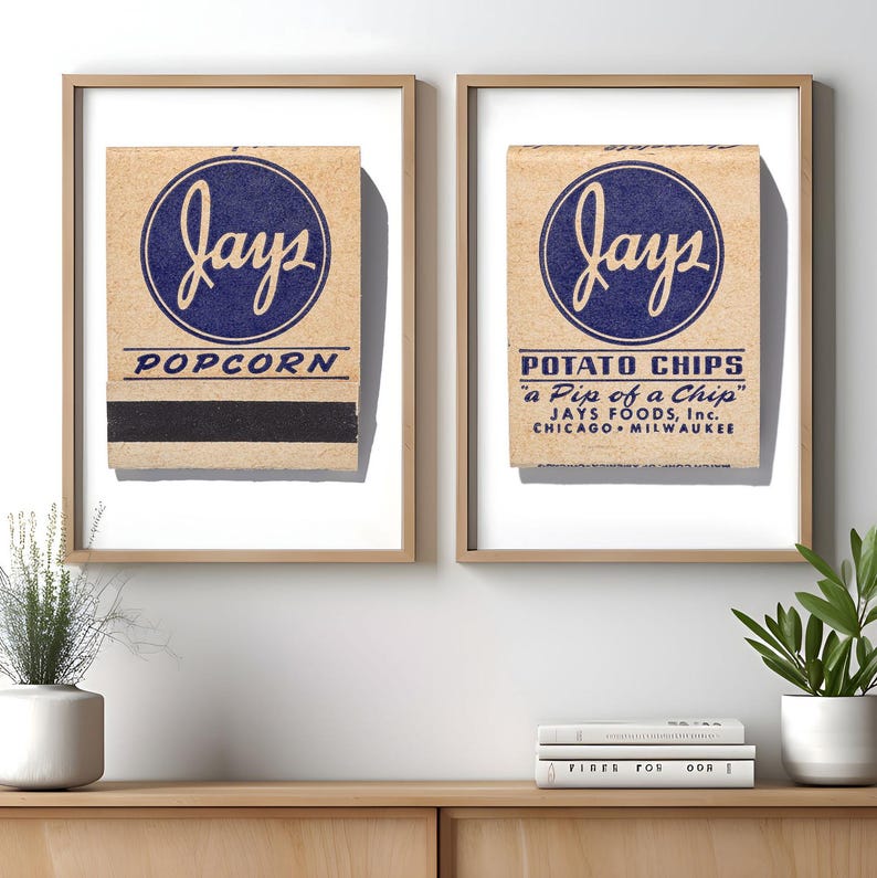 May include: Two framed prints featuring vintage Jays brand packaging. The left print displays a tan matchbook cover with a blue circular logo, the text "jays" and "POPCORN". The right print shows a tan package with "jays", "POTATO CHIPS", "a Pip of a Chip", and "JAYS FOODS, Inc. CHICAGO MILWAUKEE".