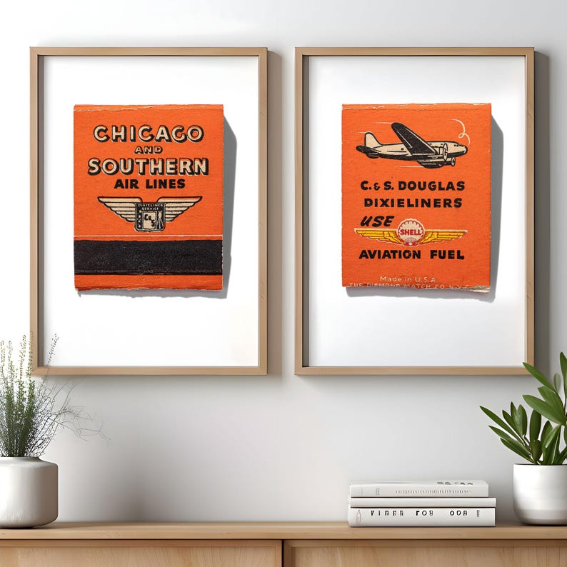 May include: Two framed vintage matchbook covers. The left cover is orange and black with the text "Chicago and Southern Air Lines" and a winged logo. The right cover is orange and black with the text "C. & S. Douglas Dixieliners Use Shell Aviation Fuel" and a plane.