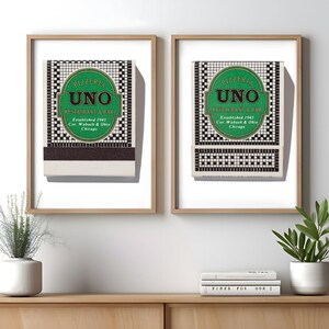 May include: Two framed prints featuring Pizzeria Uno Restaurant & Bar matchbook covers. Each print displays a green oval logo with black text reading Pizzeria Uno Restaurant & Bar, Established 1943, Cor. Wabash & Ohio, Chicago, over a black and white tile pattern.