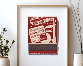May include: Framed vintage advertisement for Lion Match Co. Inc. in New York. The red and white design features the company name and the text "Manufacturers of Distinctive Book Matches for Advertising." The matchbook is displayed in a wooden frame.