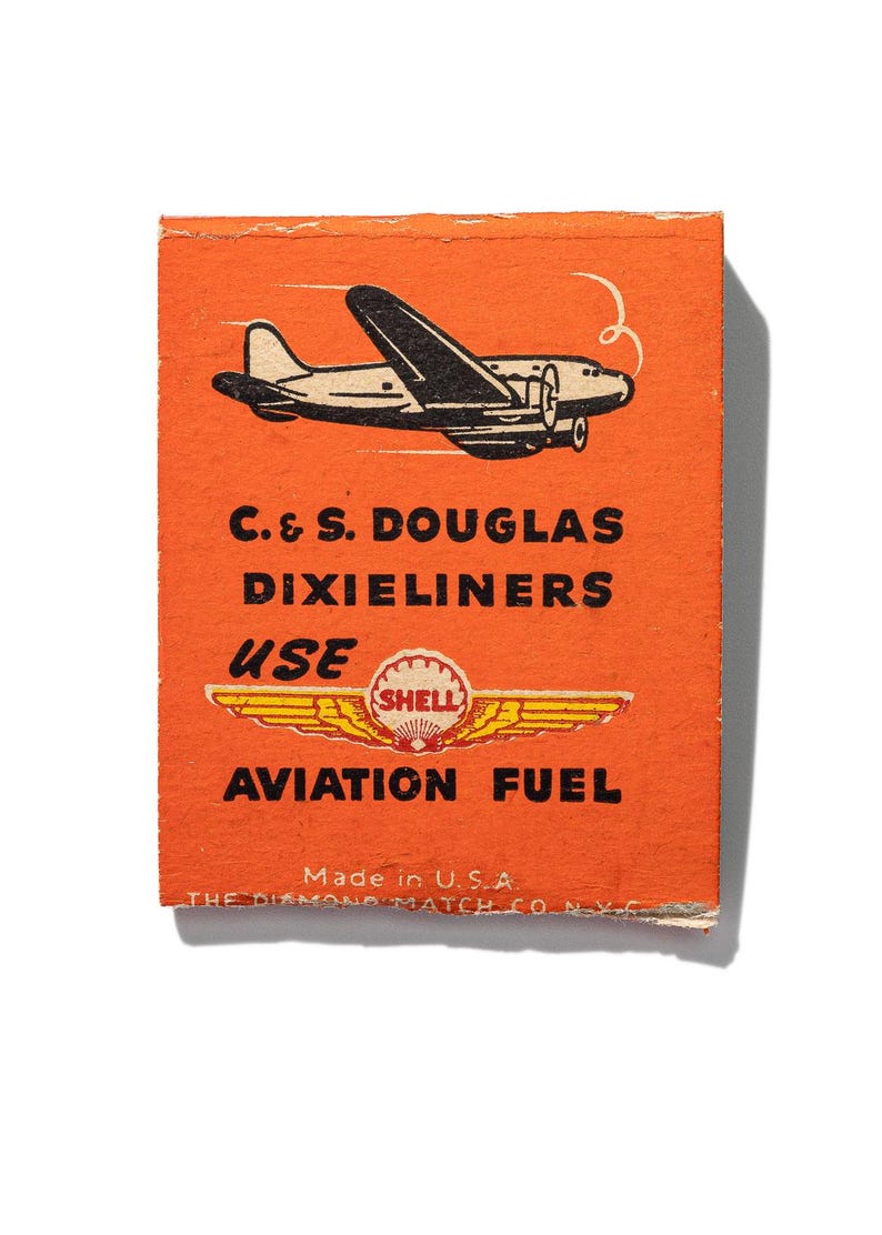 May include: Orange matchbox with a black and white illustration of an airplane flying. The text on the matchbox reads "C. & S. DOUGLAS DIXIELINERS USE SHELL AVIATION FUEL Made in U.S.A. THE DIAMOND MATCH CO. N.Y.C."