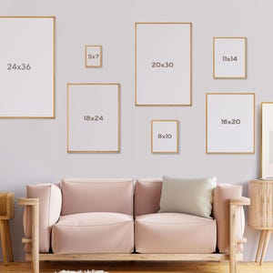 Peut inclure: Une galerie murale compos&eacute;e de neuf cadres photo de diff&eacute;rentes tailles avec des dimensions vari&eacute;es, notamment 24x36, 18x24, 20x30, 11x14, 16x20, 5x7 et 8x10 pouces. Les cadres sont tous dor&eacute;s et pr&eacute;sentent un design simple et moderne. Les cadres sont accroch&eacute;s &agrave; un mur blanc au-dessus d'un canap&eacute; rose clair.