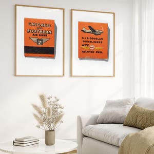 May include: Two framed vintage matchbook covers. The left matchbook cover is orange and features the text "CHICAGO and SOUTHERN AIR LINES". The right matchbook cover is orange and features a small airplane with the text "C. & S. DOUGLAS DIXIE LINERS USE SHELL AVIATION FUEL".