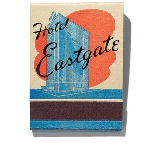 May include: Vintage matchbook cover featuring a blue and white illustration of a skyscraper with the text "Hotel Eastgate" in black cursive lettering on a cream background with a red sunburst.