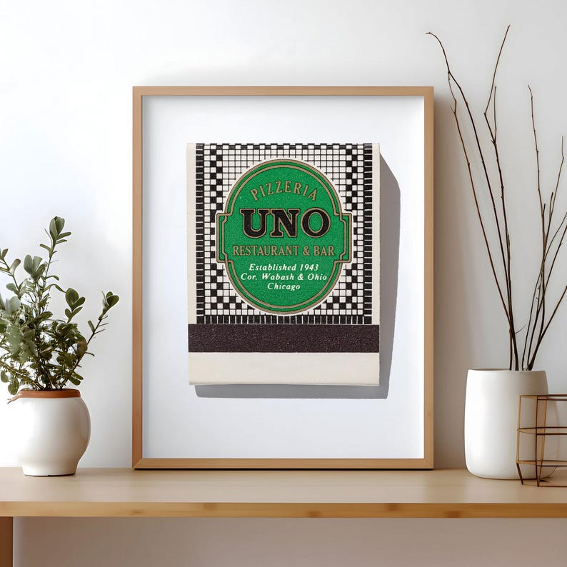 May include: A framed print featuring a vintage matchbook cover for Pizzeria Uno Restaurant & Bar. The design includes a green oval with black text reading Pizzeria Uno Restaurant & Bar, Established 1943, Cor. Wabash & Ohio, Chicago, on a grid.
