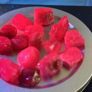 Puede incluir: Una colección de piedras lisas en forma de corazón de color rosa brillante en un plato plateado.