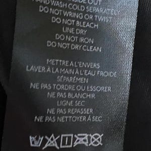 May include: Black care label with white text detailing washing instructions. The text reads "Turn inside out, hand wash cold separately, do not wring or twist, do not bleach, line dry, do not iron, do not dry clean". The label also includes French instructions and washing symbols.