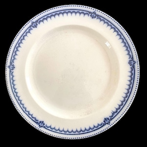 May include: White ceramic plate with a blue scalloped border and decorative corner accents. The plate has a slightly textured surface and a simple, elegant design. A classic piece for serving food.