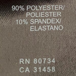 May include: A brown fabric tag with white text. The tag states "90% Polyester/Poliester 10% Spandex/Elastano" and "RN 80734 CA 31458".