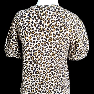 May include: A white short-sleeved shirt with a brown and black leopard print.