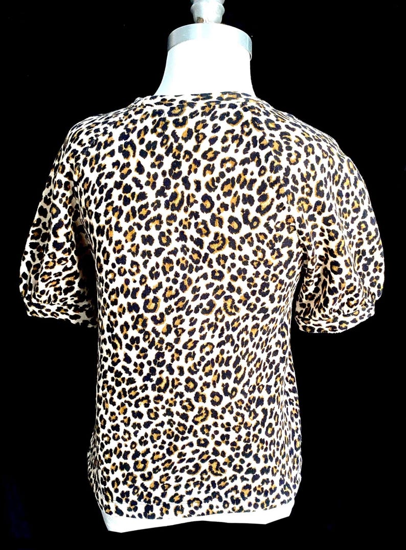 May include: A white short-sleeved shirt with a brown and black leopard print.