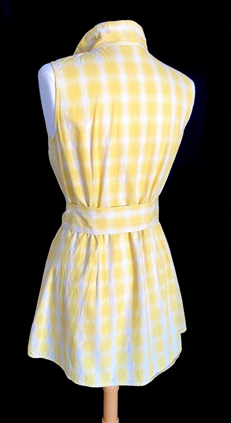K&ouml;nnte beinhalten: Ein &auml;rmelloses gelbes und wei&szlig;es Gingham-Kleid mit einem Bindeg&uuml;rtel.