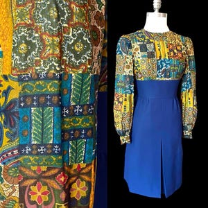 May include: A long-sleeved dress featuring a multicolored patchwork-style bodice and sleeves with intricate floral and geometric patterns in yellow, green, blue, and brown, paired with a solid royal blue skirt section that has a central front pleat.