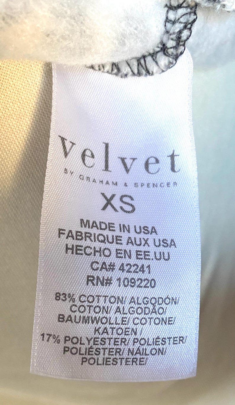 May include: White tag with black text that reads "Velvet by Graham & Spencer" and "XS". The tag also includes the following information: "Made in USA", "Fabrique aux USA", "Hecho en EE. UU", "CA# 42241", "RN# 109220", "83% Cotton/Algod&oacute;n/Coton/Algod&atilde;o/Baumwolle/Cotone/Katoen", and "17% Polyester/Poli&eacute;ster/Poli&eacute;ster/Nailon/Poliestere".