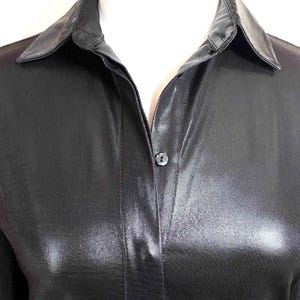 May include: A black satin shirt with a button-up closure and a classic collar.