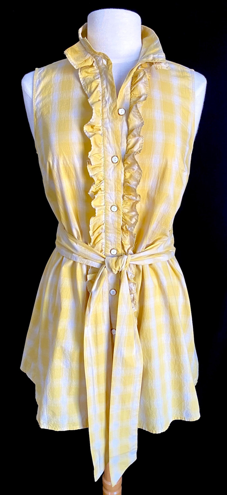 K&ouml;nnte beinhalten: Ein gelbes und wei&szlig;es kariertes, &auml;rmelloses Kleid mit R&uuml;schenkragen und einem Selbstbinderg&uuml;rtel.