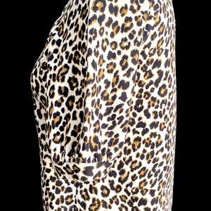 May include: A white, brown, and black leopard print top with a short sleeve and a round neckline.