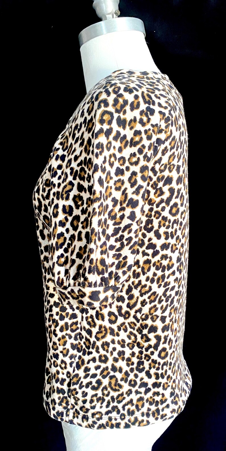 May include: A white, brown, and black leopard print top with a short sleeve and a round neckline.