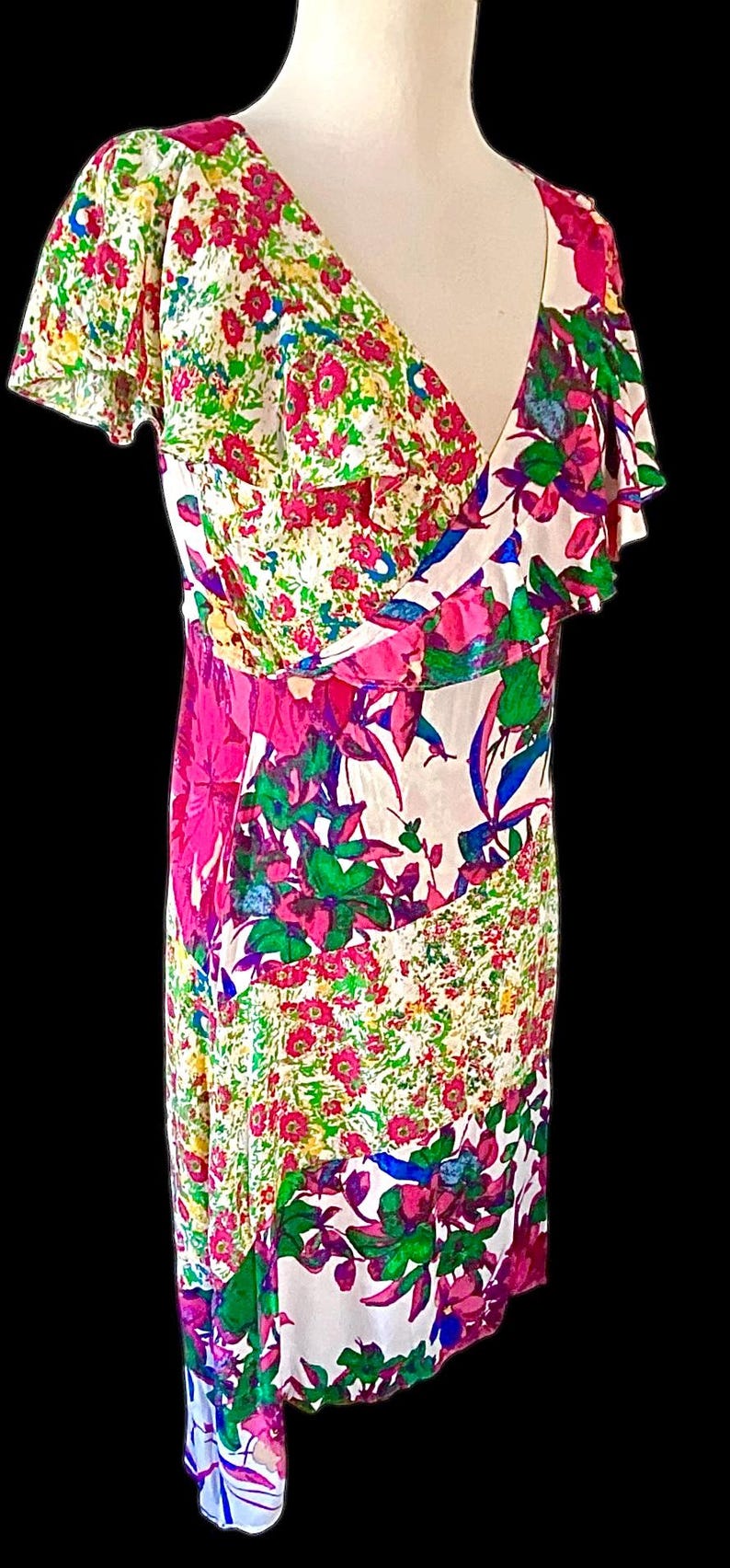 May include: A colorful floral print dress with a V-neckline and flutter sleeves. The dress features a mix of pink, green, blue, and white floral patterns. The dress is a vibrant and eye-catching piece.