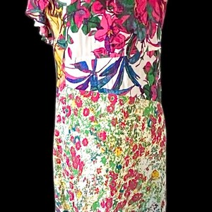 May include: A floral print dress on a mannequin. The dress features a white background with large pink, purple, and blue flowers. The dress has short sleeves and a knee-length hemline.