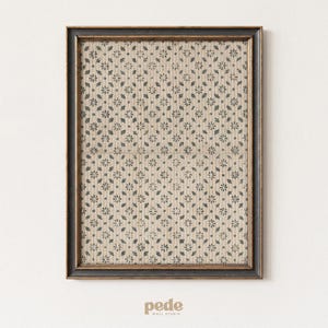 May include: A framed print with a dark brown frame. The print displays a repeating pattern of small, dark blue floral and leaf motifs on a beige background. The print is centered on a white wall.